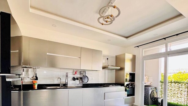 Et moderne køkken med rustfrie stålgrejs, et stort vindue og et rent, minimalistisk design.