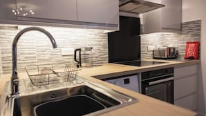 Una cocina moderna con un lavamanos de acero inoxidable, una campana extractora negra y una encimera de madera.