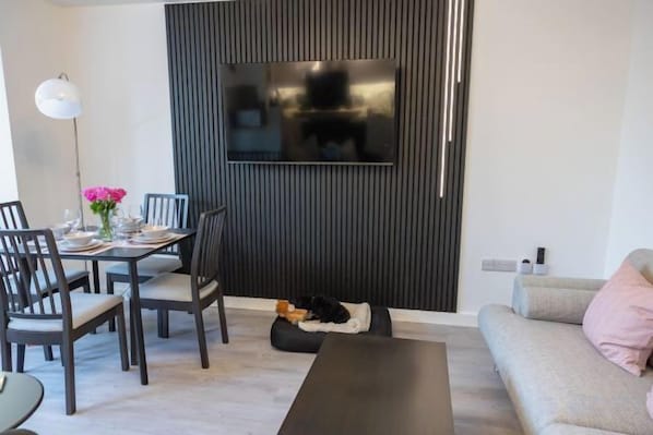 Ein modernes Wohnzimmer mit Essbereich, einer Couch und einem an der Wand befestigten Fernseher.