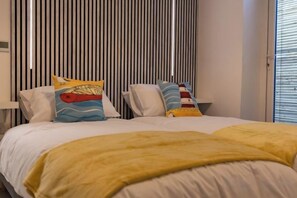 A bed with a yellow blanket and two pillows with nautical designs. - Sunbeam House Apartment 1 (Heysham)