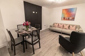 A dining area with a table set for four, a sofa, and a modern chair. - Sunbeam House Apartment 1 (Heysham)