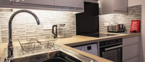Una cocina moderna con un lavamanos de acero inoxidable, una tetera y un tostador.