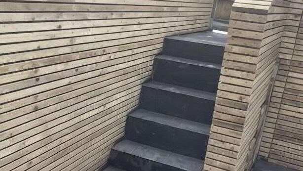 Una escalera con paneles de madera en las paredes y suelo de baldosas.