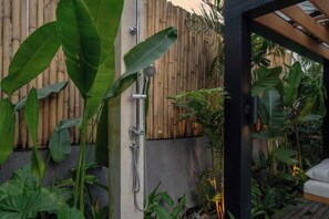 A shower area with a bamboo fence, concrete wall, and various tropical plants. - Villa Laia by BaliSuperHost (Bali)