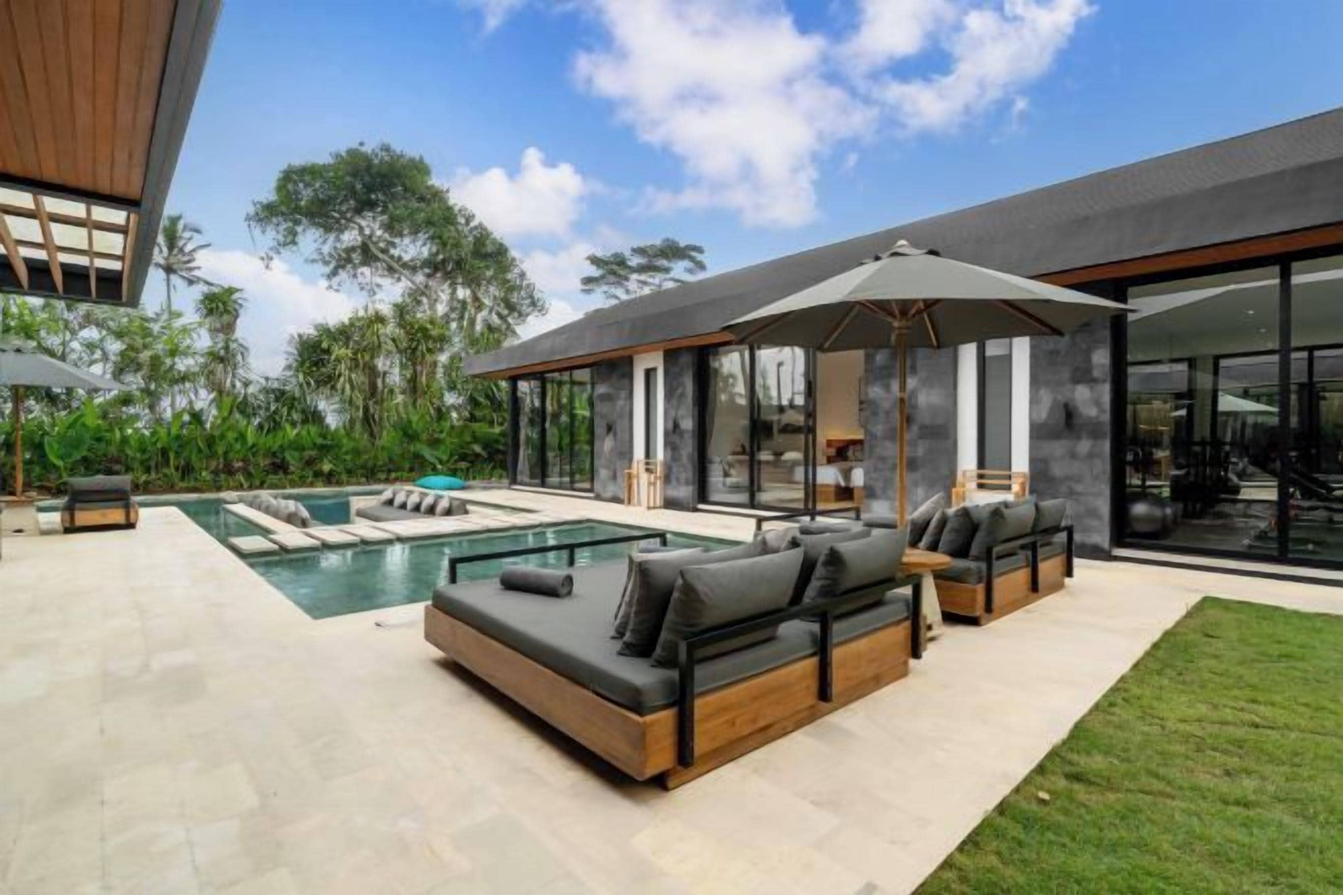 A modern outdoor living area with a pool, outdoor seating, and a covered patio.