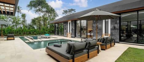 A modern outdoor living area with a pool, outdoor seating, and a covered patio.