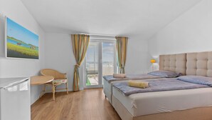 Un dormitorio con cama, escritorio, silla y ventana con cortinas.