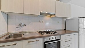 Eine moderne Küche mit Gasherd, Backofen, Spüle aus Edelstahl und weißen Schränken.