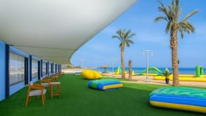 A covered outdoor area with artificial grass, seating, and inflatable play structures. - Single Room with Sea View – Aquatic Village, Red Sea Resort (Hurghada)