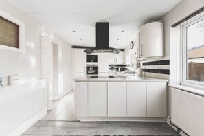 Een moderne keuken met witte kasten, een centraal eiland en een zwarte afzuigkap.