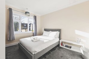 Une chambre d’hôtel avec un lit, une table de chevet et une fenêtre avec des rideaux.
