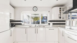 Una cucina moderna con mobili bianchi, un'ampia finestra e un orologio a vista.