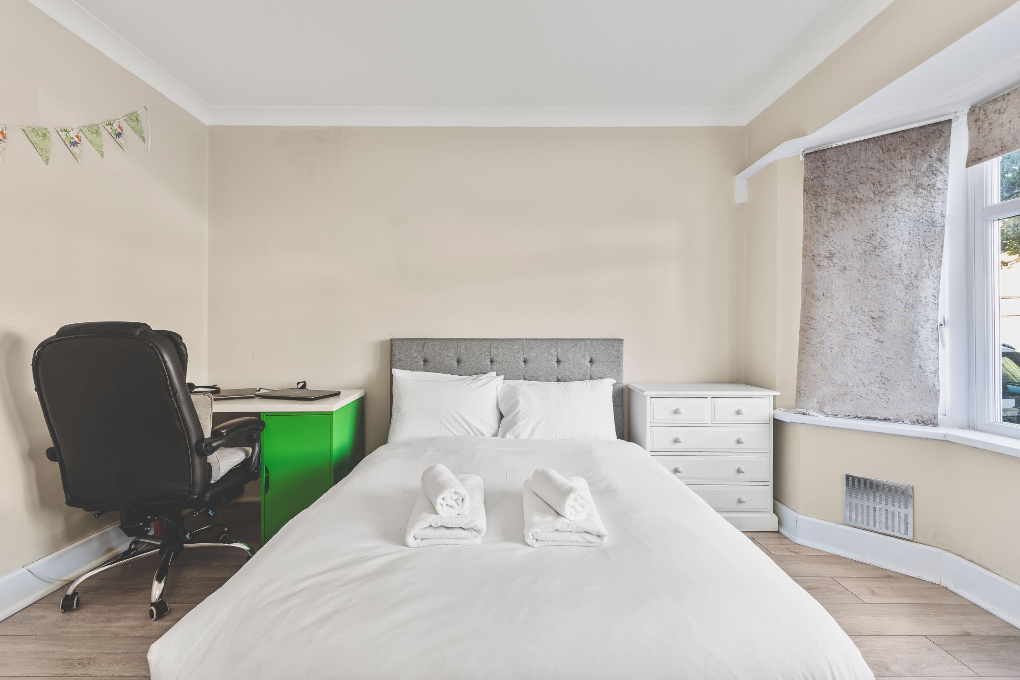 A bedroom with a bed, a desk, a chair, and a window.