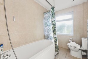 Une salle de bain avec une baignoire, des toilettes et un rideau de douche.