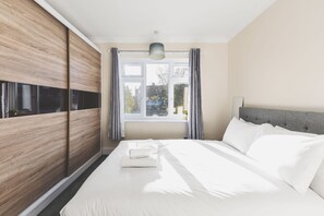 Une chambre moderne avec un grand lit, une armoire et une fenêtre avec des rideaux.