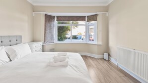 Una camera da letto con un letto grande, una finestra con tende, un termosifone e vista all'esterno.
