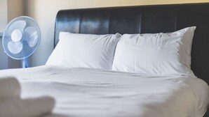 Una cama con sábanas blancas y un cabecero oscuro.