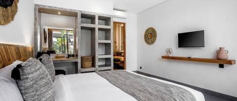 A bedroom with a bed, a TV, a shelf, and a wardrobe.