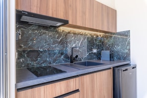 A modern kitchen with a built-in stove, a sink, and a dishwasher. - Manthos Beachfront Apartments (Laganas)