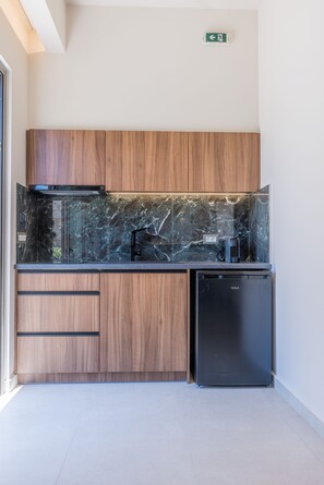 A modern kitchen with wooden cabinets, a black countertop, and a black refrigerator. - Manthos Beachfront Apartments (Laganas)