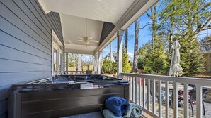 A covered outdoor area with a hot tub, a bench, and a wicker basket with towels.
