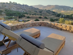 Eine Dachterrasse mit Liegestühlen und einer Steinmauer.