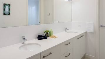 Un baño moderno con dos lavamanos, un espejo grande y un perchero para toallas.