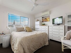 A bedroom with a bed, a dresser, a chair, a TV, and a window with blinds. - Relaxing Pool Hervey Bay Getaway Steps from Beach (Torquay)