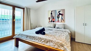 Un dormitorio con una cama grande, vigas de madera, un candelabro en el techo, un armario y un cuadro en la pared.