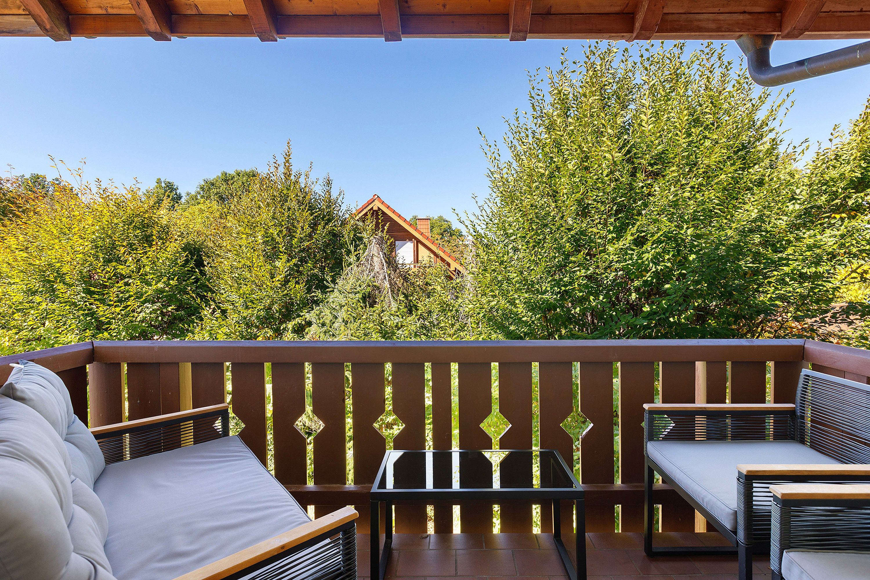 Een overdekt terras met uitzicht op een gebouw en bomen.