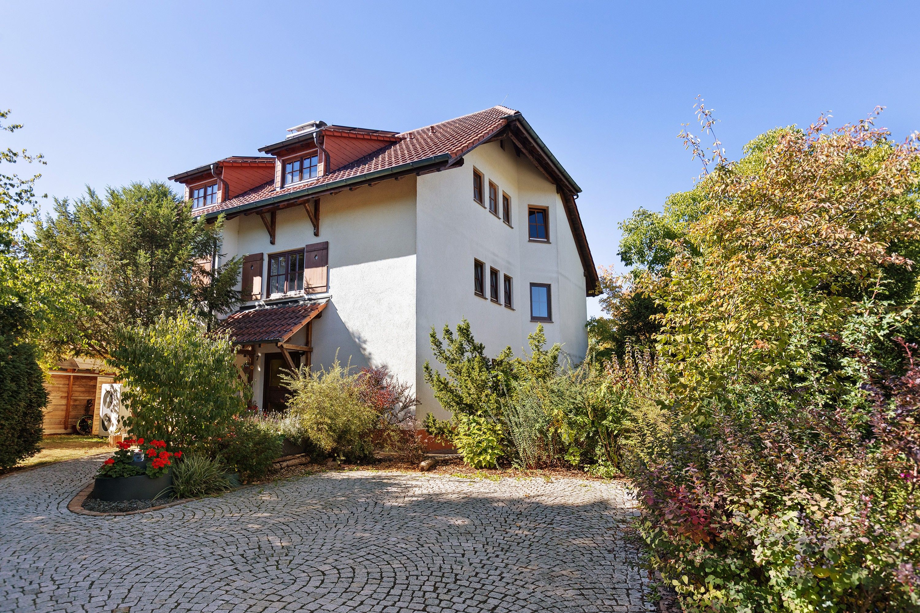 Une maison à deux étages avec une allée pavée et un jardin.