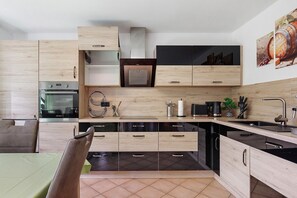 A modern kitchen with wooden cabinets, a built-in oven, and a sink. - Apartment '1, Stockwerk 1, 86qm' with Balcony and Wi-Fi (Königsfeld im Schwarzwald)