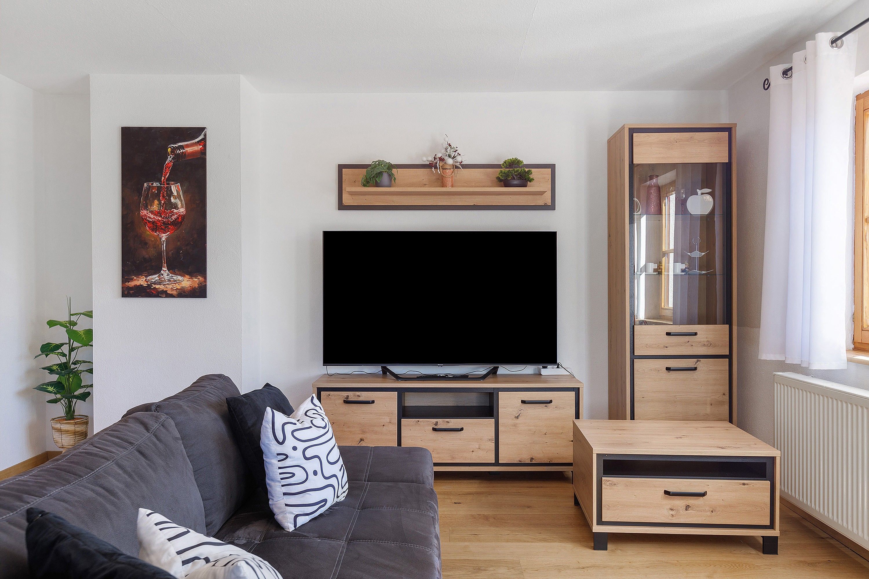 Un salon moderne avec un téléviseur à écran plat, des meubles en bois et une plante en pot.