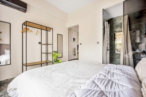 A modern hotel room with a large bed, a wardrobe with a mirror, and a bathroom with a shower and a marble wall. - Sunny Apartment Next to the sea Amazing View (Piraeus)