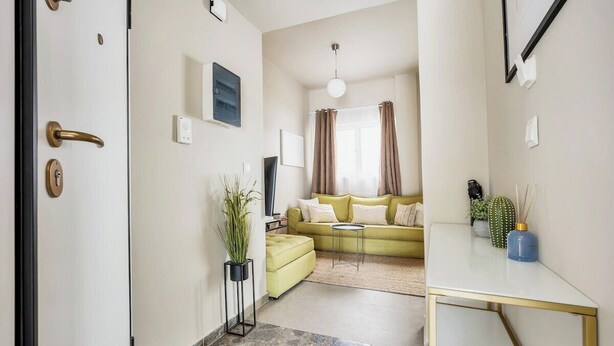 A modern living room with a sofa, a coffee table, and a TV. There is a plant and a cactus on the side. - Sunny Apartment Next to the sea Amazing View (Piraeus)