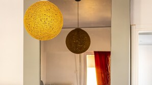 A modern living room with a fireplace, a large mirror, and hanging spherical light fixtures. - Sunny 3bd Flat Acropolis View (Athens)