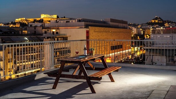 A wooden picnic table on a rooftop terrace with a cityscape view in the background. - Sunny 3bd Flat Acropolis View (Athens)