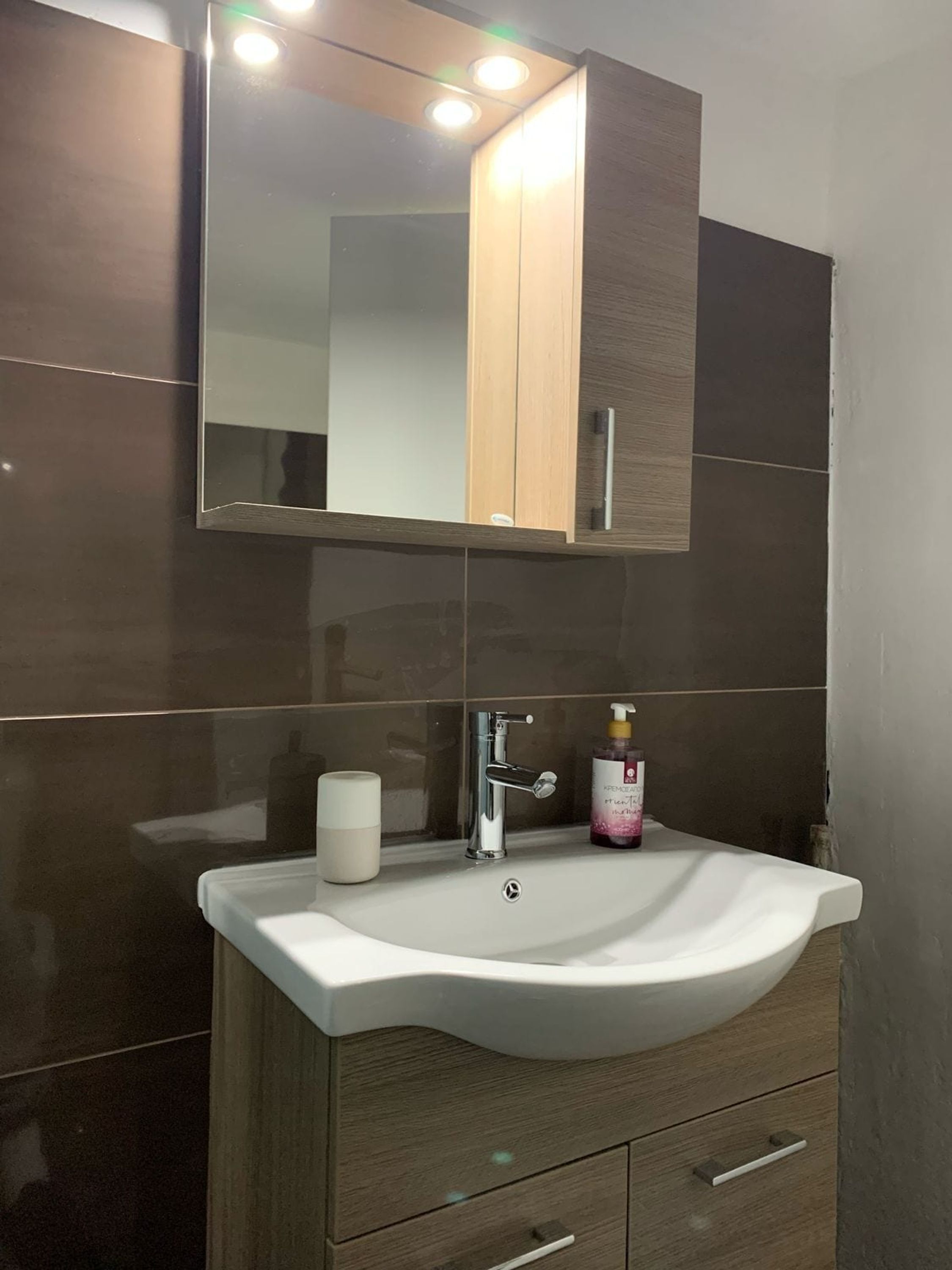 A bathroom with a white sink, a mirror, and a wooden cabinet.
