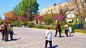 Ένας δρόμος στρωμένος με λιθόπλινθους, με πεζούς, δέντρα και ένα ιστορικό κτίριο στο βάθος.