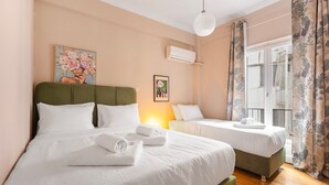 A hotel room with two beds, a green headboard, white bedding, a painting on the wall, an air conditioning unit, and a window with curtains. - Sunny Cozy 3bd apt Just a min Away to Acropolis (Athens)