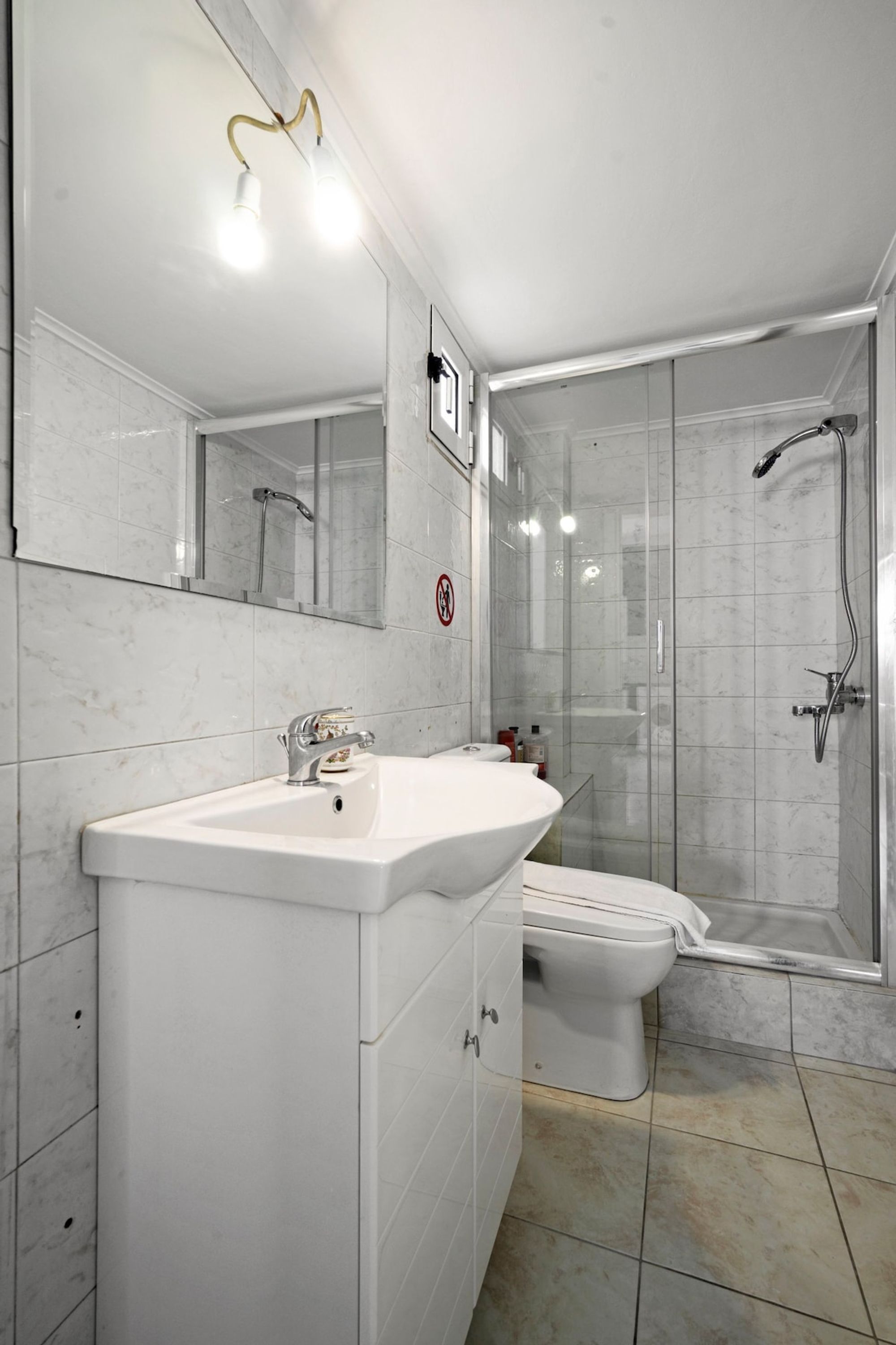 A bathroom with a white sink, mirror, and shower.