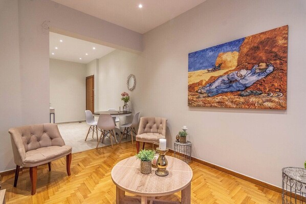 A modern living room with a round wooden coffee table, two armchairs, and a painting of a landscape on the wall. - Prime 2BR Apartment Next to Kallimarmaro Stadium (Athens)