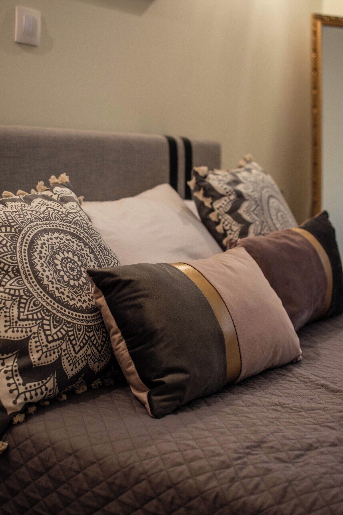 A bed with a quilted cover and multiple pillows, including a decorative one with a paisley pattern.