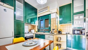 A modern kitchen with green cabinets, a wooden dining table, and yellow chairs. - Sunny 3bd Cozy Flat Spectacular Acropolis View (Athens)