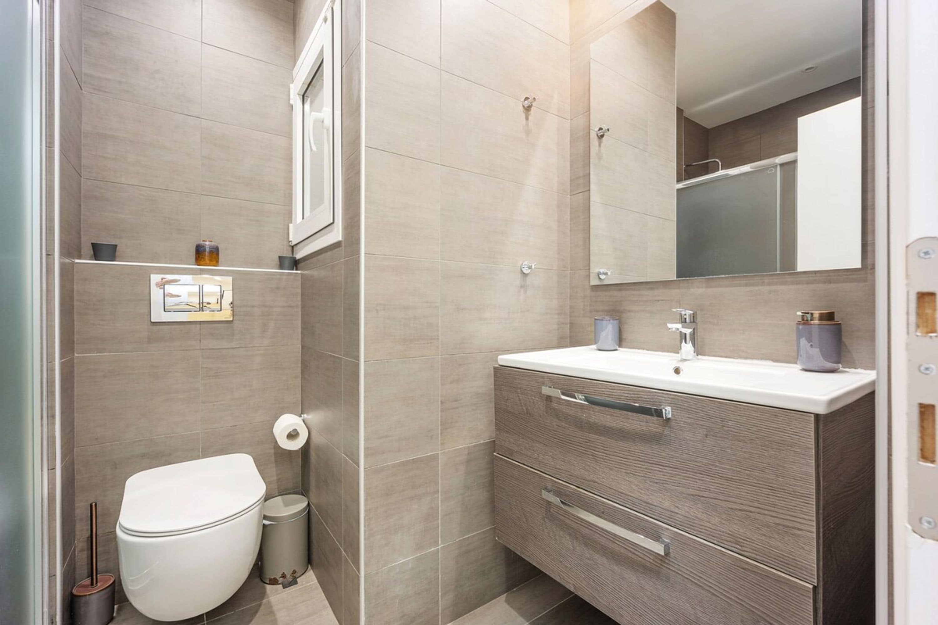 Un baño moderno con inodoro, lavamanos y espejo.