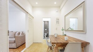 A modern room with a wooden dining table, two chairs, a large mirror, and a beige sofa. - Modern Cozy Apartment (Athens)
