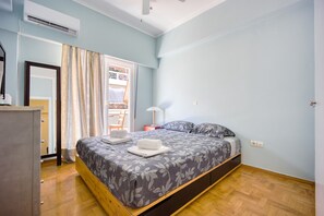 A bedroom with a bed, a nightstand, a lamp, and an air conditioning unit. - Sunny 1-bedroom Apt 10 Min Walk to Acropolis (Athens)