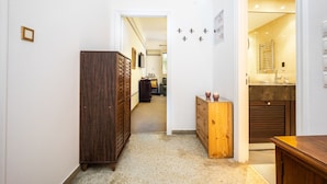 Ein Flur mit einem Holzschrank, einer kleinen Holzkommode und einem Badezimmer mit Waschbecken und Spiegel.