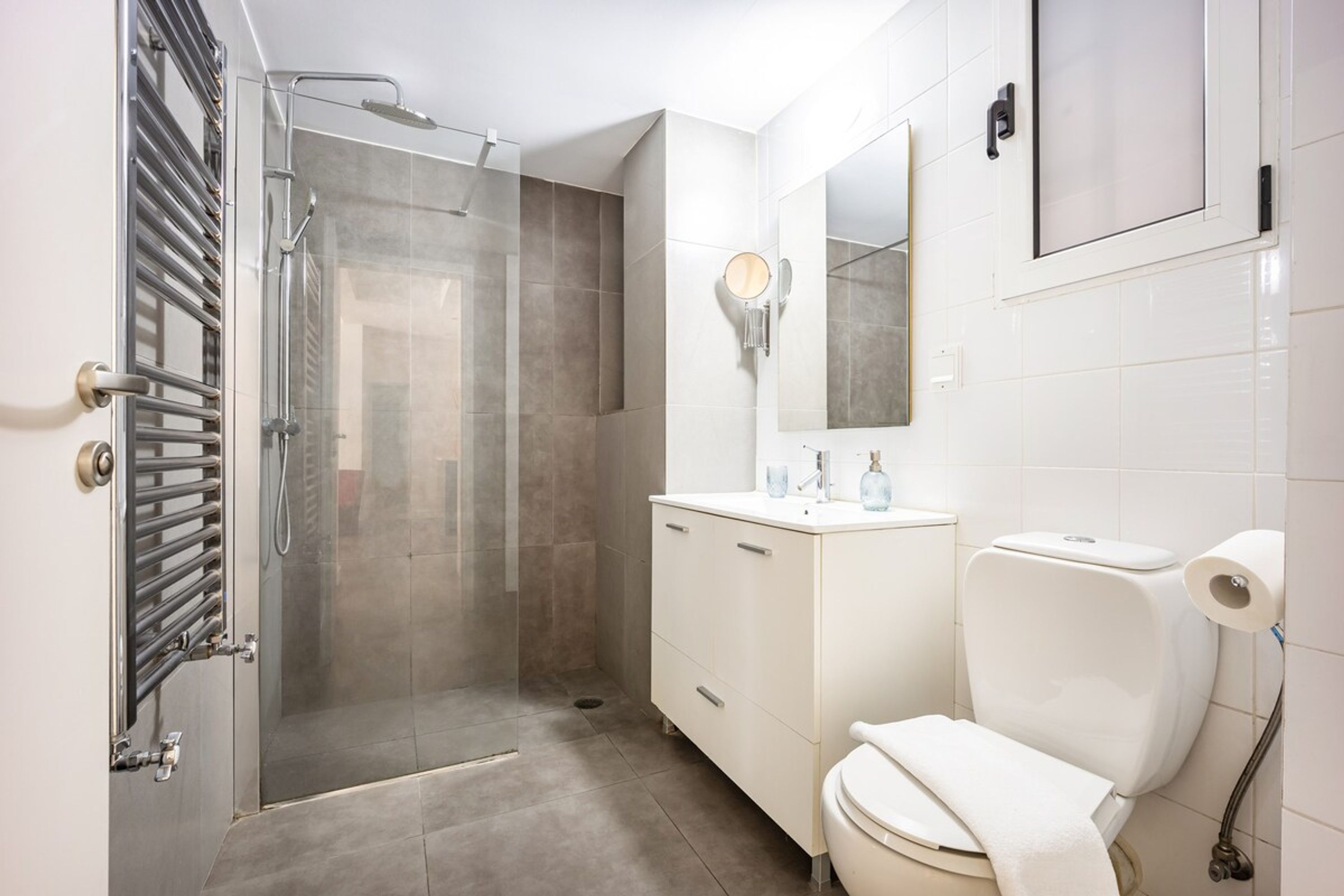 A modern bathroom with a glass-enclosed shower, a white sink with a mirror, and a toilet.