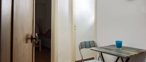 A room with a table, chairs, a clock, and a door.
